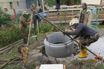 Spouštění betonové skruže do studny.