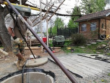 Muž vytahuje kameny ze studny.
