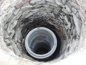 Kamená studna přeskružená betovými skružemi.